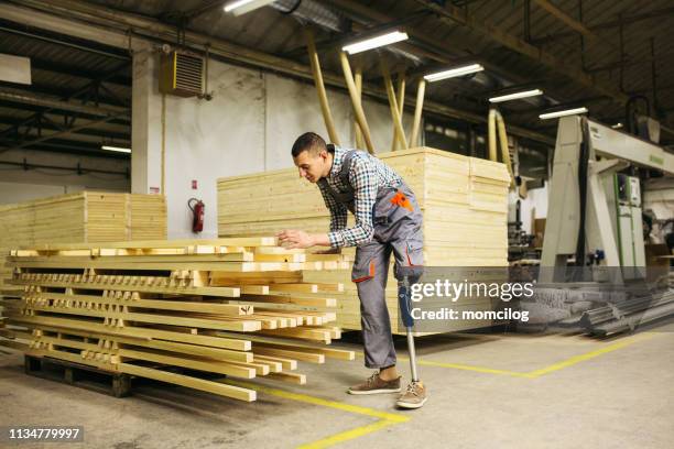 ウッドプランクを運ぶ仕事で義足を持つ若い大工 - wood worker posing ストックフォトと画像