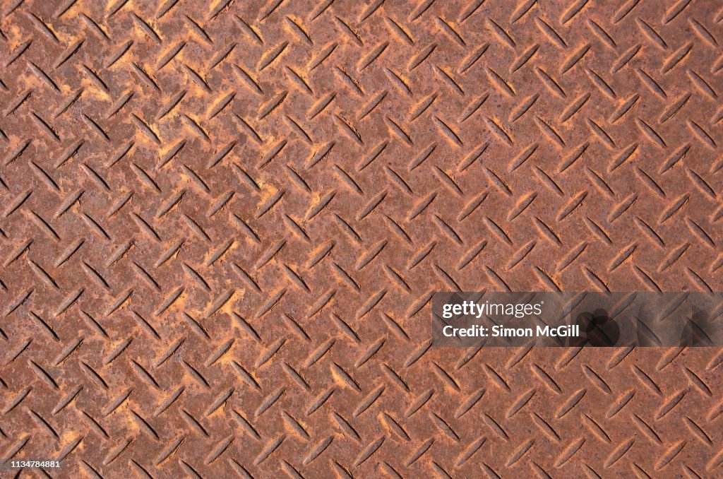 Rusty steel plate with cross-hatch non-slip texture pattern