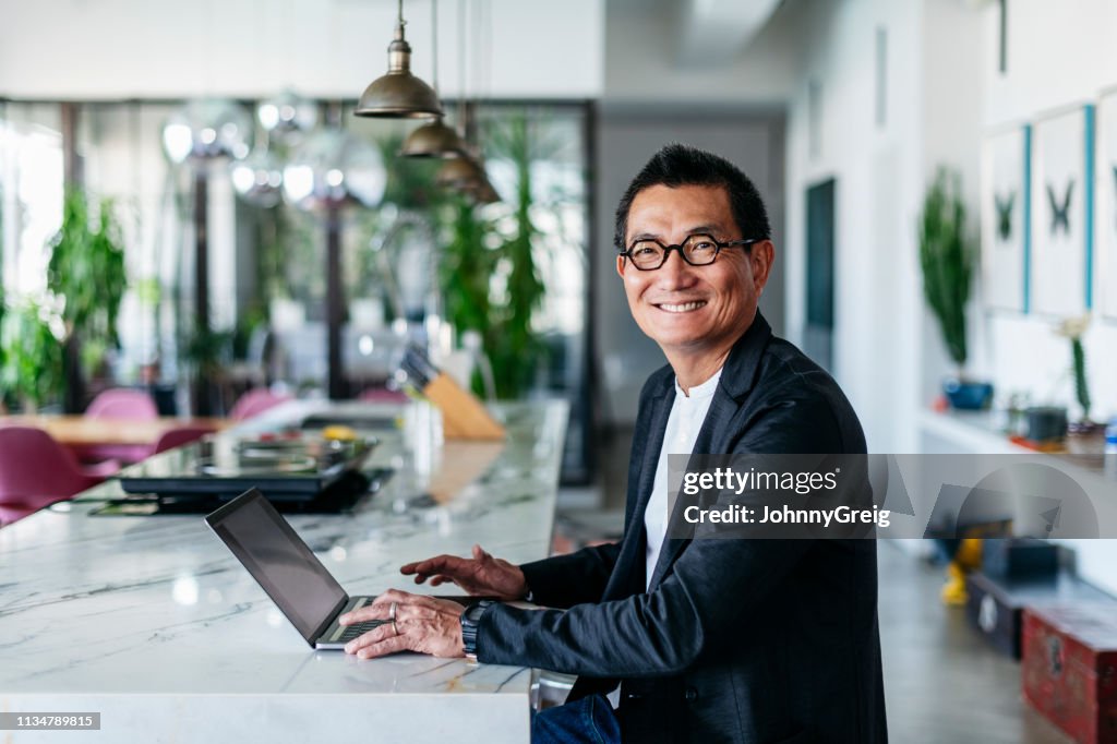 Chinese businessman in contemporary cafe using laptop