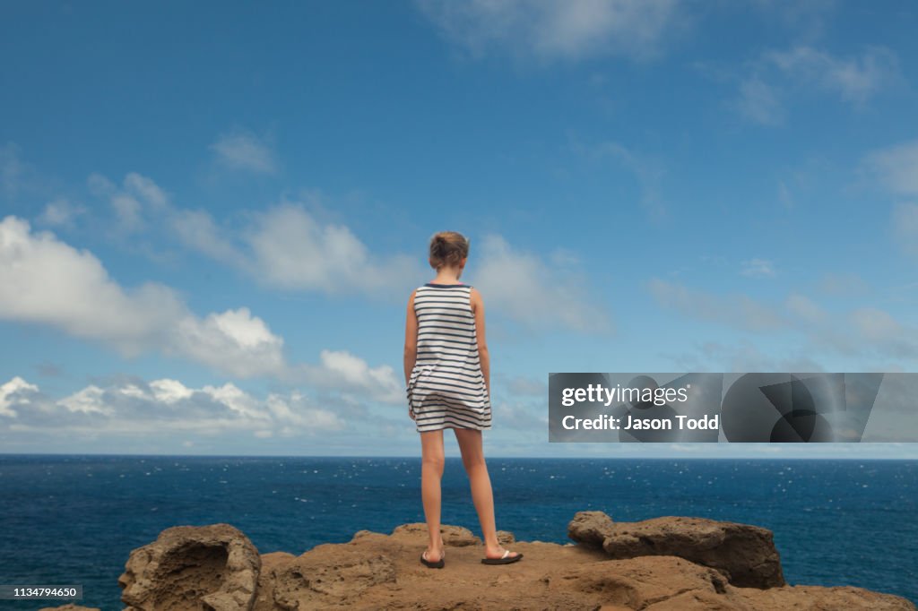 Girl at the edge of a rock cliff with facing ocean near Nakalele Point and blowhole
