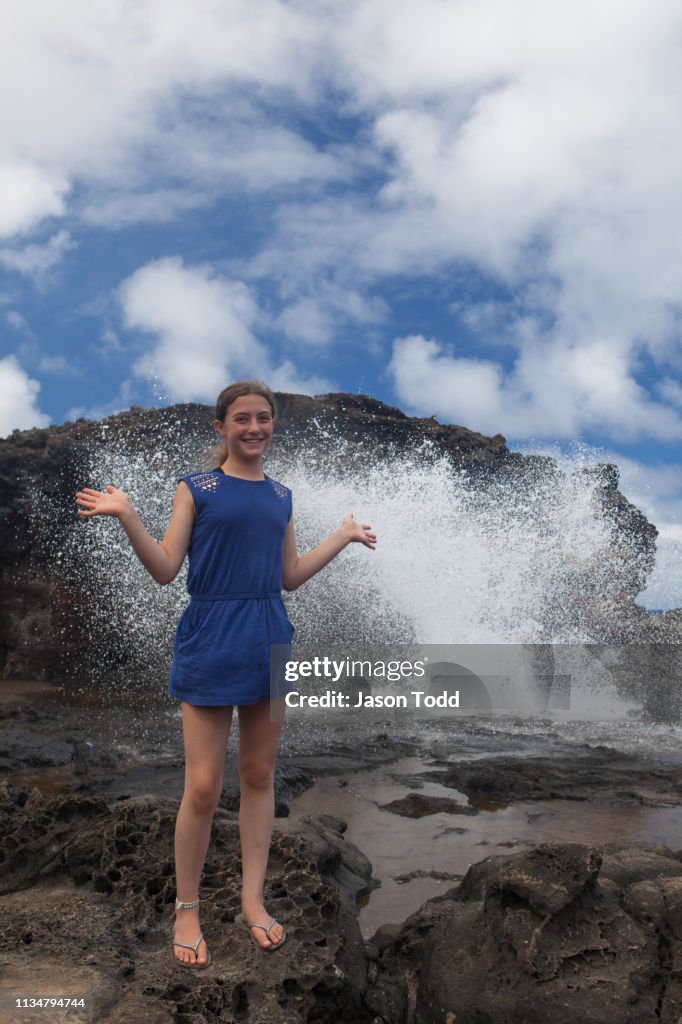 Girl making excited face with hands up in front of blowhole at Nakalele Point in West Maui