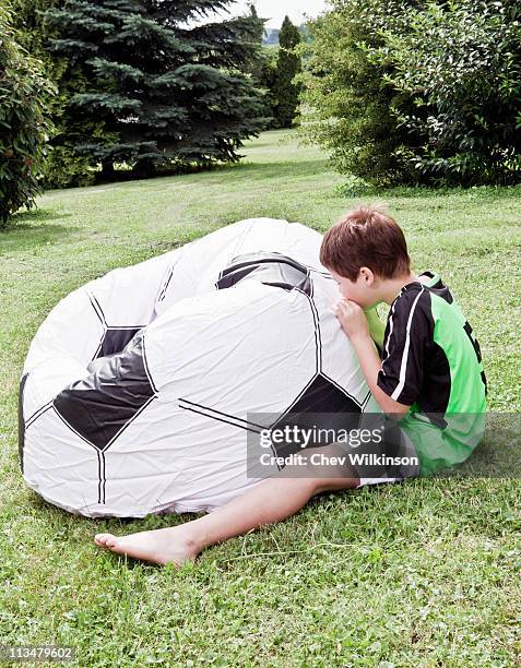 boy inflating giant football - inflate stockfoto's en -beelden