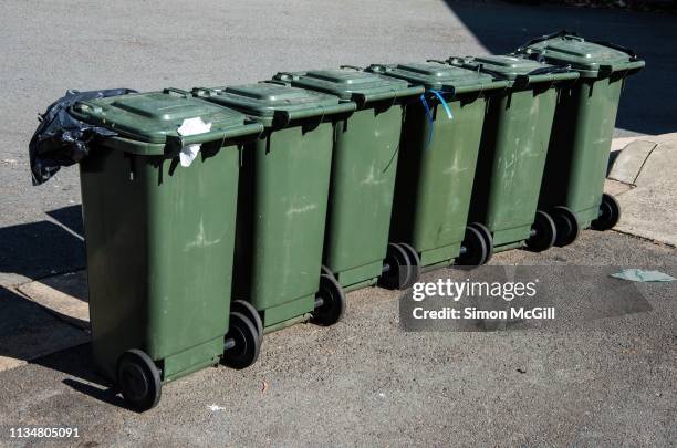 row of six wheeled plastic garbage bins - vuilnisemmer op wielen stockfoto's en -beelden