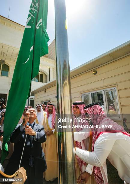 Iraqi Foreign Minister Mohammad Ali al-Hakim raises the Saudi flag alongside Saudi Arabia's Trade and Investment Minister Majed al-Qasabi and Energy...