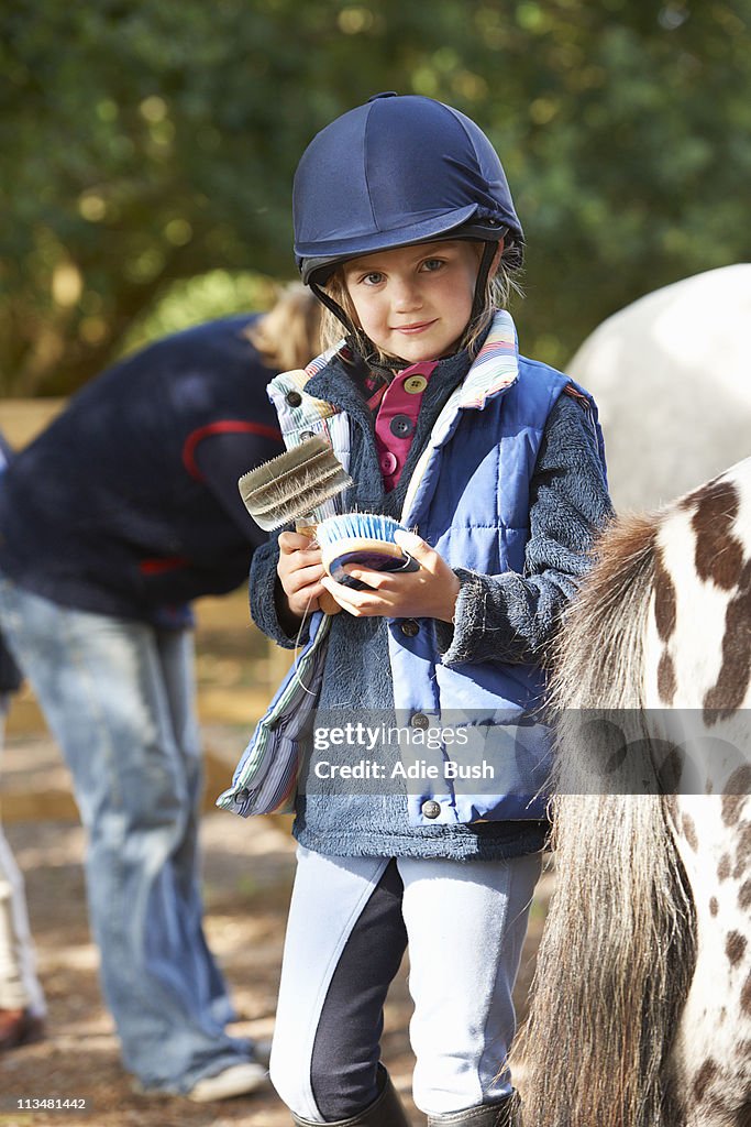 Young girl grooming her pony