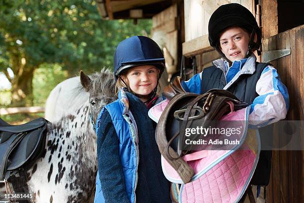 two girls holding saddles with pony - pony 個照片及圖片檔