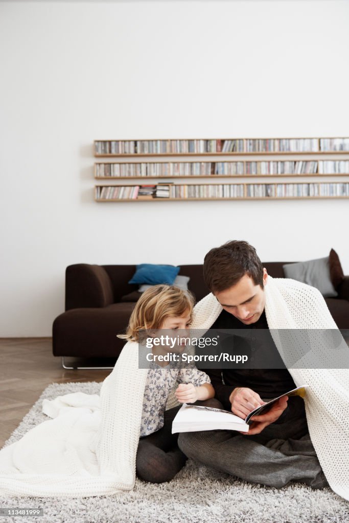 Father and daughter under blanket