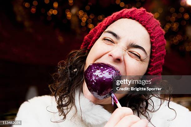 woman taking a bite of candied apple - mujer and manzana and frontal fotografías e imágenes de stock