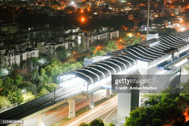 aerial shot of lights of delhi metro station with cityscape and traffic light trails in background - indian hyderabad metro rail stock pictures, royalty-free photos & images