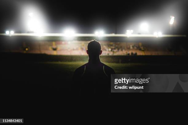 athlet zu fuß in richtung stadionsilhouette - football stock-fotos und bilder
