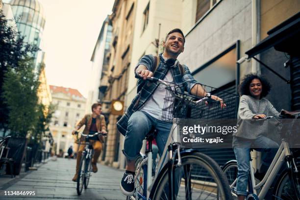 friends riding bicycles in a city - friends cycling stock pictures, royalty-free photos & images
