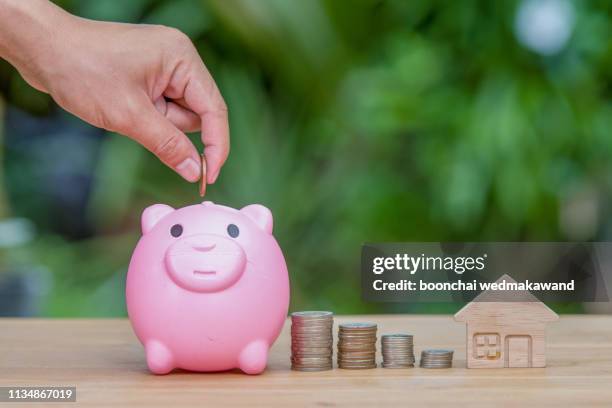 piggy bank with coin on old wooden table - silver putter stock pictures, royalty-free photos & images