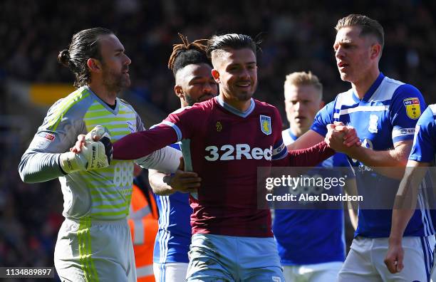 Jack Grealish of Aston Villa is helped up by Lee Camp and Michael Morrison of Birmingham City after colliding with a pitch invader during the Sky Bet...