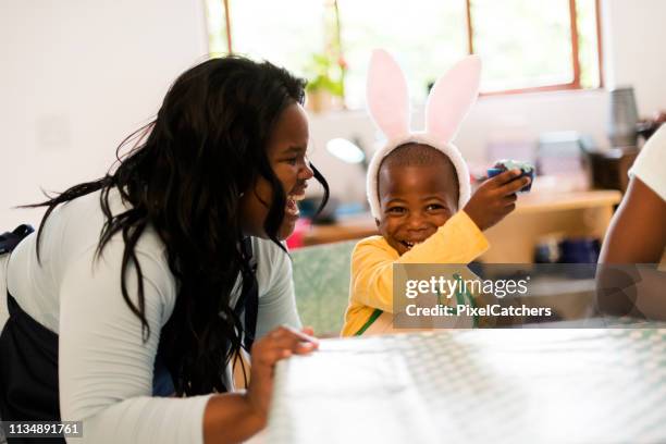 young mom pretends to want a bite of son's cupcake - african easter stock pictures, royalty-free photos & images