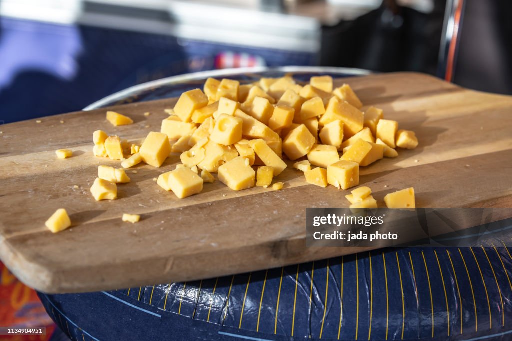 Many small pieces of sliced cheese on a wooden board