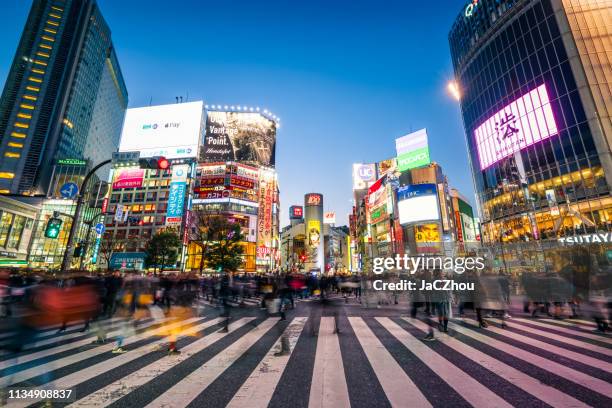 fußgänger überqueren straßenübergang bei shibuya-kreuzung mit bewegungsunschärfe - tokyo travel destinations stock-fotos und bilder
