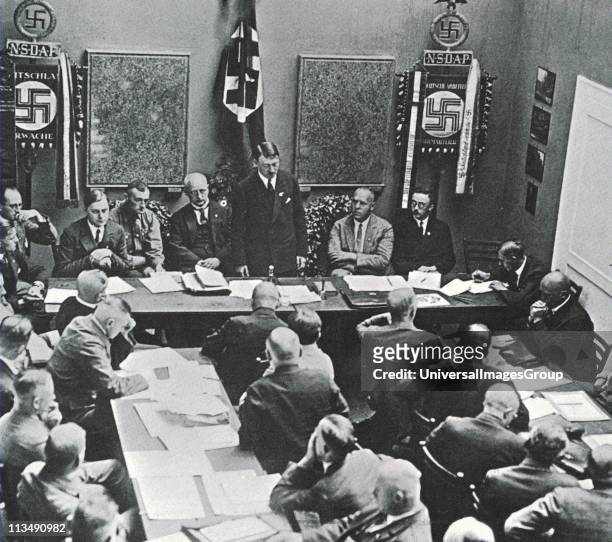 Hitler in Munich adressing a meeting of the NSDAP in 1925. Third to the left of Hitler is Alfred Rosenberg, on the right are Gregor Strasser and...