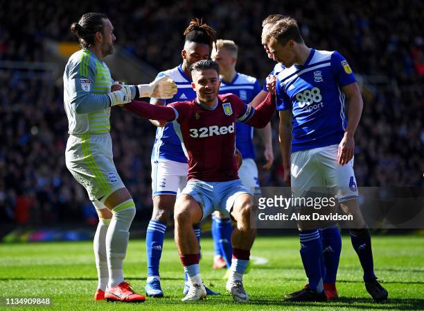 Jack Grealish of Aston Villa is helped up by Lee Camp of Birmingham City and Maikel Kieftenbeld of Birmingham City after being struck by a fan during...