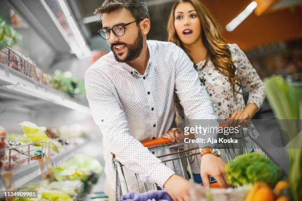 choosing vegetables at supermarket. - young woman trolley stock pictures, royalty-free photos & images
