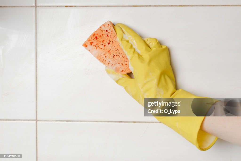 Close-up woman cleaning tiled surface in kitchen.