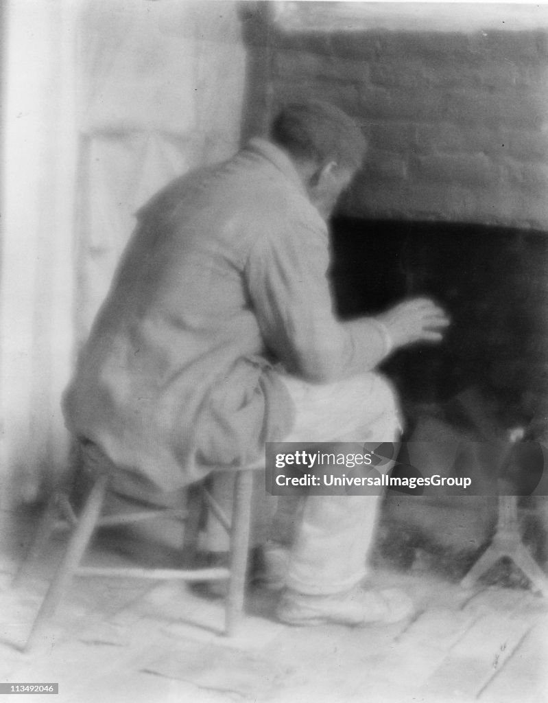 African American, possibly a former slave, sitting warming himself by the fire in his room. Photograph c1800. ...