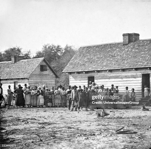 Plantation slaves gathered outside their huts, Virginia, America. Photograph c1860.
