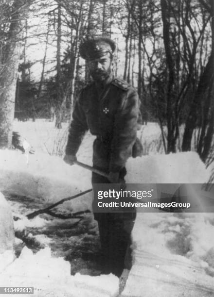 Russian Revolution: Emperor Nicholas II shovelling snow in the grounds of Tsarskoe Selo, Russia where he was imprisoned with the royal family in...