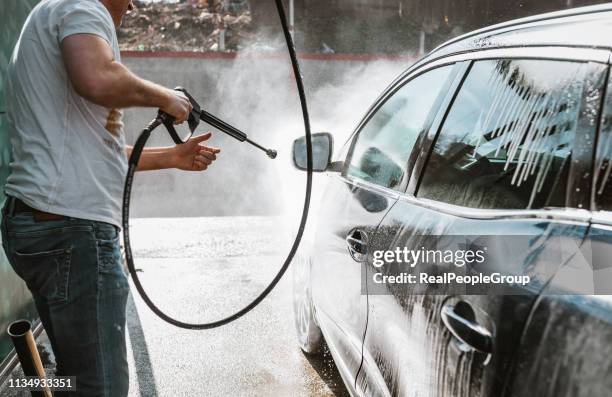 man wassen van zijn auto met hoge druk wassen - auto druppel stockfoto's en -beelden