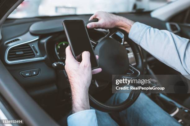guida pericolosa durante la scrittura di sms. uomo con cellulare in mano e giovane donna a guida in auto in autostrada. - distrarsi foto e immagini stock