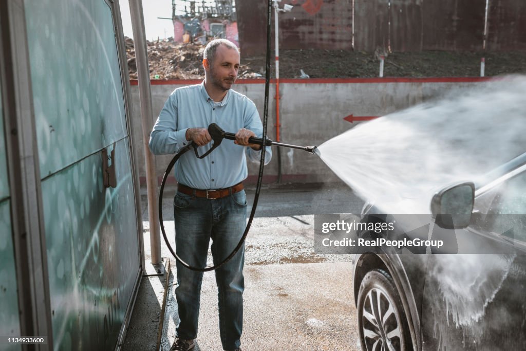 Man washing his car with high-pressure washing