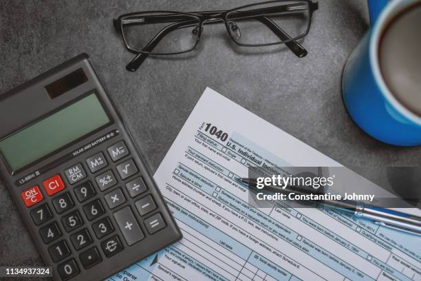 printed tax form on work desk with calculator and pen - 1040 tax form stock-fotos und bilder