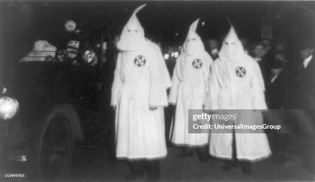 Three Ku Klux Klan members standing beside automobile driven by Klan members. 1922 March ...