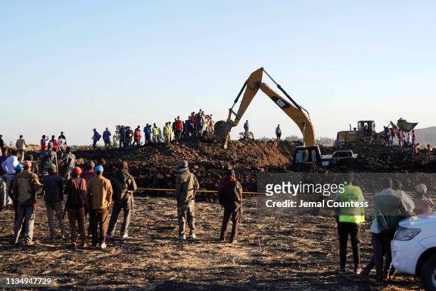 Rescue and recovery personnel use an earth mover to recover debris from a crater where Ethiopian Airlines Flight 302 crashed in a wheat field just...