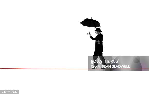 walking tightrope with umbrella - hochseil stock-fotos und bilder