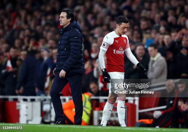 Mesut Ozil of Arsenal walks past Unai Emery, Manager of Arsenal after being substituted off during the Premier League match between Arsenal FC and...