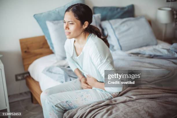 stomach pain attack - women touching herself in bed stock pictures, royalty-free photos & images