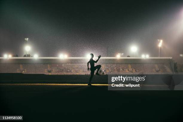 lauftraining beim aufwärmen junger athleten vor stadion-flutlicht - famous footballers silhouette stock-fotos und bilder