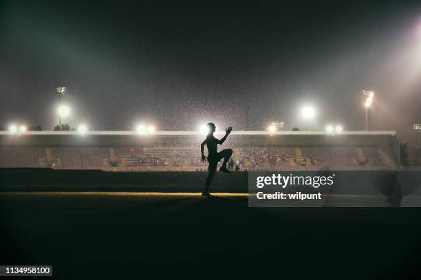 running exercising warming up young athlete in front of stadium floodlights - runner warming up stock pictures, royalty-free photos & images