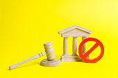 Wooden judge hammer and government building on a yellow background. Court. Concept of the state judicial system. Laws and the constitution, lack of Supremacy of rights and freedoms
