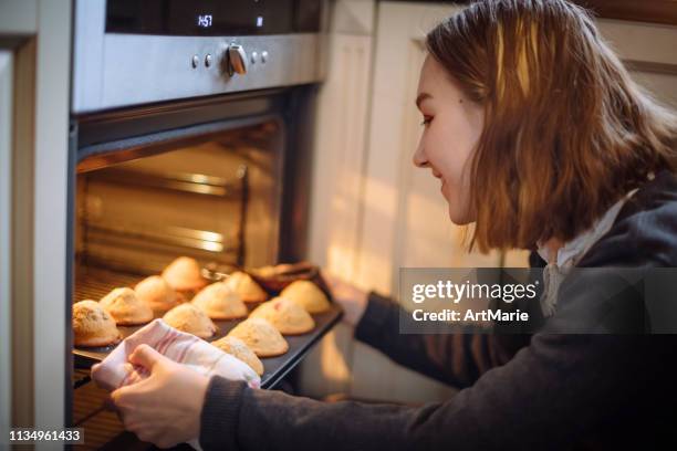 gelukkig meisje krijgt taarten uit de oven in de keuken - muffin stockfoto's en -beelden
