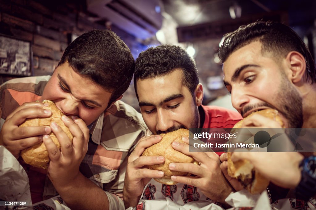 Guys eating burgers