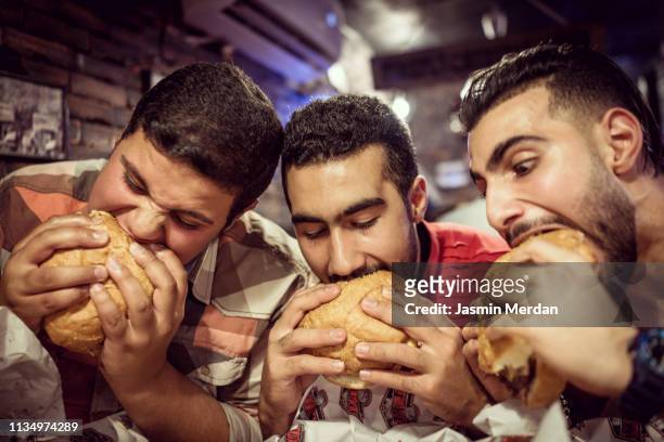 guys eating burgers - ungesunde ernährung stock-fotos und bilder