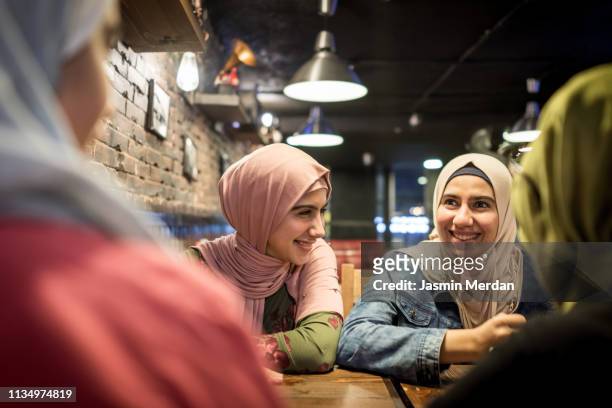 arab teenage girls having fun together in restaurant - arabische familie stock-fotos und bilder