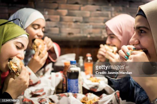 muslim teenage girls having a lunch break together in restaurant - young muslim stockfoto's en -beelden