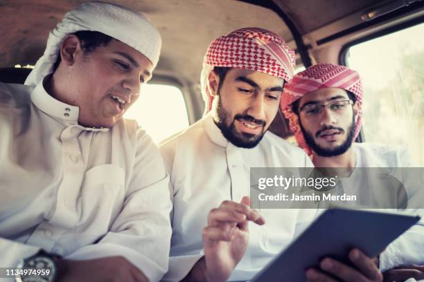 arab young traditional men in car using tablet - saudi telecom stock pictures, royalty-free photos & images