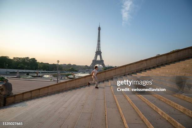 sporty young man running up the stairs at the eiffel tower in paris - paris sport stock pictures, royalty-free photos & images