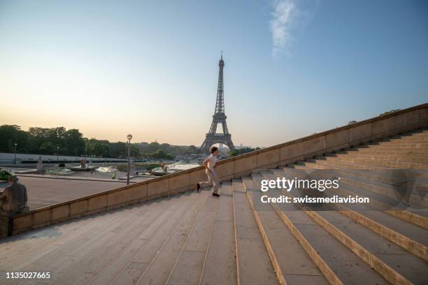 sporty young man running up the stairs at the eiffel tower in paris - eiffel tower stairs stock pictures, royalty-free photos & images