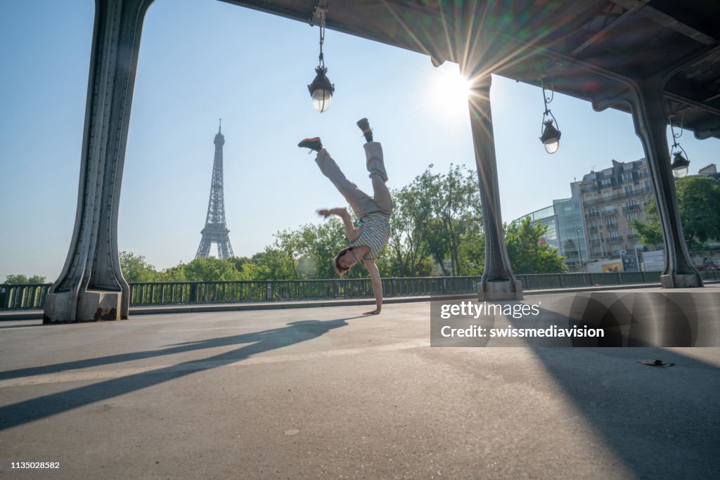 Sporty young man doing handstand in Paris under bridge, France