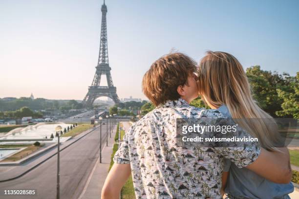 junges ehepaar am eiffelturm in paris betrachtet die urbane skyline - couple paris tour eiffel trocadero stock-fotos und bilder