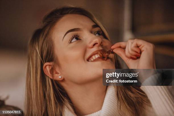 mujer joven comiendo aperitivo - sentarse a comer fotografías e imágenes de stock